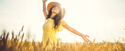 Woman smiling while holding a heart-shaped bowl of fresh fruit and wellness supplements